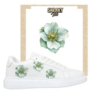 Könnte beinhalten: Weiße Turnschuhe mit floralem Design. Die Schuhe haben eine große, hellgrüne und weiße Blumengrafik auf der Seite und kleinere Blumengrafiken. Der Text "Sneaky Tats" befindet sich in der oberen rechten Ecke.