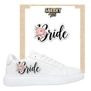 Könnte beinhalten: Weiße Sneaker mit floralem "Bride"-Design. Das Wort "Bride" ist in schwarzer Schrift geschrieben, begleitet von einer rosa und weißen Pfingstrose. Das Bild enthält auch einen passenden Aufkleber mit dem Text "Sneaky Tats".