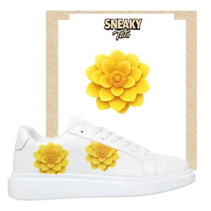May include: White sneakers with a yellow flower design. The sneakers have a thick sole and the flower design is on the side of the shoe. The image also includes a large yellow flower graphic and the text "Sneaky Tats".