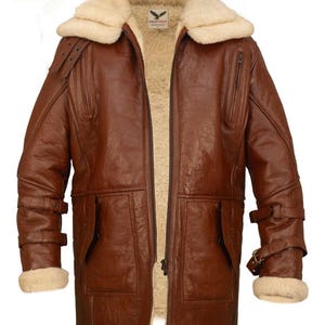 May include: Brown leather jacket with a cream-colored shearling lining and collar. Features include a zipper closure, multiple pockets, and adjustable straps on the sleeves. The jacket has a classic aviator style.