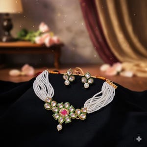 May include: A white beaded necklace and matching earrings set. The necklace features a floral pendant with a central pink stone, surrounded by green and clear accents. The earrings have a similar design with a pearl drop.