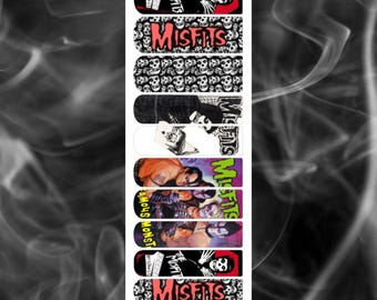 May include: A selection of nail art decals with diverse designs. The designs include the word "Misfits" in red, skull patterns, and illustrations of the band. The top and bottom of the image have the text "A Touch of Evil".