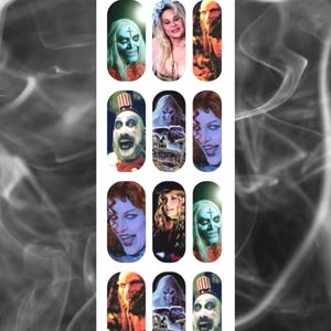 May include: A sheet of press-on nails featuring various horror-themed images. The designs include portraits of characters with pale skin, and images of a haunted house. The text "A Touch Of Evil" is at the top and bottom of the sheet.