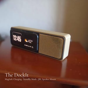 May include: A rectangular, cream-colored speaker with a black display showing the time and temperature. The speaker has a gold mesh grill on the right side. The text "The DockIt" is visible at the bottom.