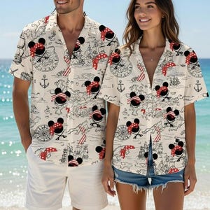 Puede incluir: Camisas a juego de manga corta con un diseño de Mickey Mouse con temática pirata. Las camisas presentan un fondo crema con ilustraciones en negro y rojo de barcos piratas, mapas, anclas y Mickey Mouse con una bandana roja.