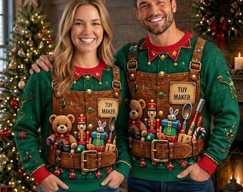 May include: Two green long-sleeve sweaters featuring a printed design of brown overalls with a belt, a toy maker sign, and various toys including a teddy bear, a nutcracker, and a rabbit. The sweaters have red cuffs and collar accents.
