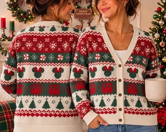 Op de afbeelding: Een crèmekleurig vest met knoopsluiting en een feestelijk patroon in rood en groen. Het gebreide ontwerp bevat herhalende motieven van kerstbomen, pepermuntjes en muizenoren met strikjes, afgewerkt met een geribbelde zoom en boorden.