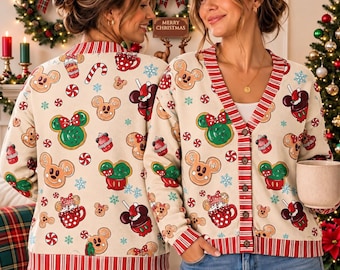 Op de afbeelding: Een beige vest met V-hals voorzien van een herhalend kerstpatroon van peperkoek Mickey en Minnie Mouse hoofden, zuurstokken, pepermuntjes en sneeuwvlokken, afgewerkt met rood-witte gestreepte boorden langs de knoopsluiting en zoom.
