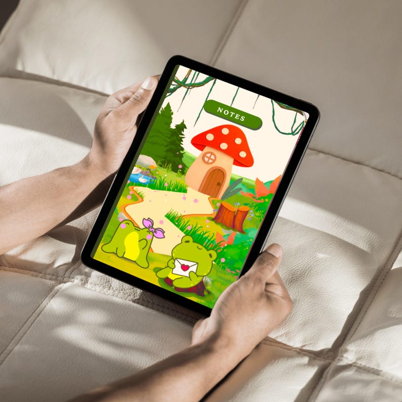 Op de afbeelding: Een tablet met een grillige illustratie van een paddenstoelenhuis met een rood en wit gestippelde kap, een kikker met een brief en het woord "NOTES". De sc&egrave;ne speelt zich af in een levendig groen landschap.