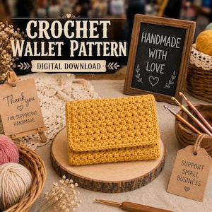 May include: A mustard yellow crochet wallet with a textured stitch pattern, displayed on a round wooden slice. The scene includes a sign reading CROCHET WALLET PATTERN DIGITAL DOWNLOAD, a chalkboard saying HANDMADE WITH LOVE, and crochet hooks.