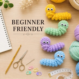 May include: Four crocheted worms in yellow, light green, purple, and blue with googly eyes, alongside a gold crochet hook, metal scissors, a needle, stitch markers, a notebook with the text BEGINNER FRIENDLY, and a measuring tape.