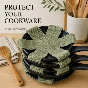 May include: A stack of black frying pans separated by sage green crocheted star-shaped pan protectors. The text PROTECT YOUR COOKWARE DIGITAL DOWNLOAD is visible at the top. The protectors feature a circular centre with six radiating arms.
