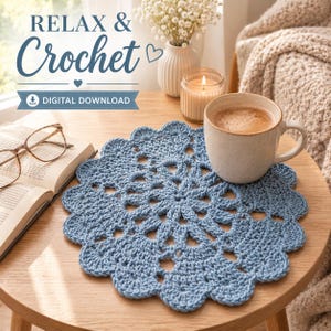 May include: A round, dusty blue crocheted doily with a scalloped edge and intricate openwork pattern. The text "RELAX & Crochet" and "DIGITAL DOWNLOAD" is visible in the upper left corner of the image, alongside a book, glasses, and a mug.