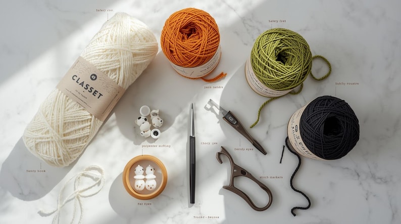 May include: An assortment of craft supplies for knitting and crochet. Includes cream-colored yarn with a label, orange, green, and black yarn balls, a crochet hook, stitch markers, safety eyes, and other tools.