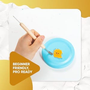 May include: A light blue, round craft piece with a yellow lion design. A craft tool with a wooden handle and metal tip is held above the piece. The text "BEGINNER FRIENDLY, PRO READY" is in a yellow triangle.