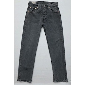 Könnte beinhalten: Eine Jeans aus verwaschenem, schwarzem Denim. Die Jeans hat einen Knopfverschluss, fünf Taschen und Kupfernieten. Die Jeans hat eine gerade Bein und scheint getragen zu sein. Die Jeans wird auf einer weißen Oberfläche präsentiert.