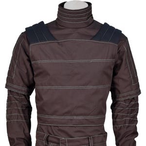 Puede incluir: Mono marr&oacute;n con cuello alto y hombreras. La prenda presenta costuras blancas horizontales en el pecho y las mangas. Las hombreras son de un tono marr&oacute;n m&aacute;s oscuro. El mono parece estar hecho de un material duradero.