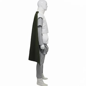 May include: A costume featuring a white turtleneck, a white top with gray sleeves, gray pants, and white boots. A dark green cape drapes over the shoulder. The outfit is displayed on a mannequin.