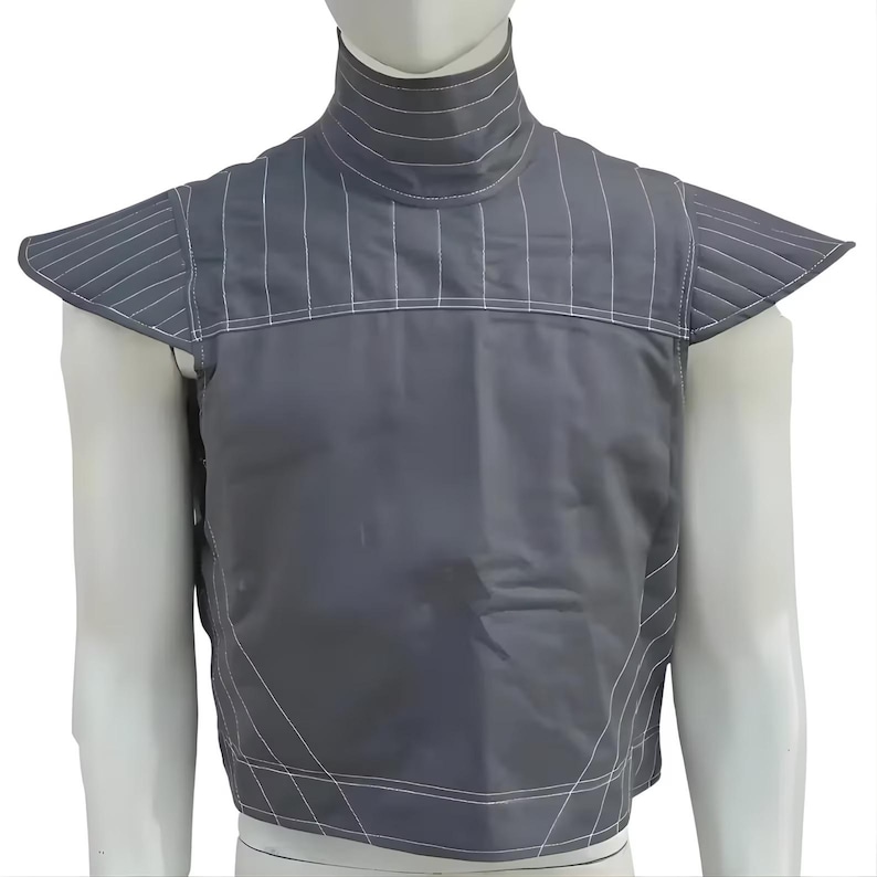 Op de afbeelding: Een grijze vest met een hoge kraag en schoudervullingen. De vest heeft witte verticale en horizontale stikseldetails. Het kledingstuk wordt op een mannequin getoond.