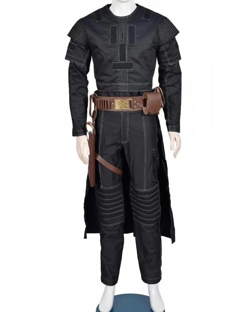 May include: Black costume with white stitching, featuring a long-sleeved top with shoulder accents and a matching pair of pants. The outfit includes a brown belt with a gold buckle, a holster, and a pouch. The costume is displayed on a mannequin.