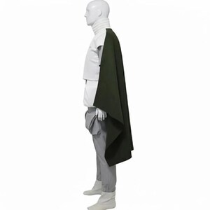 May include: A mannequin wearing a white turtleneck, white top, gray pants, and white boots. A dark green cape is draped over the mannequin's shoulder. The outfit is displayed against a white background.