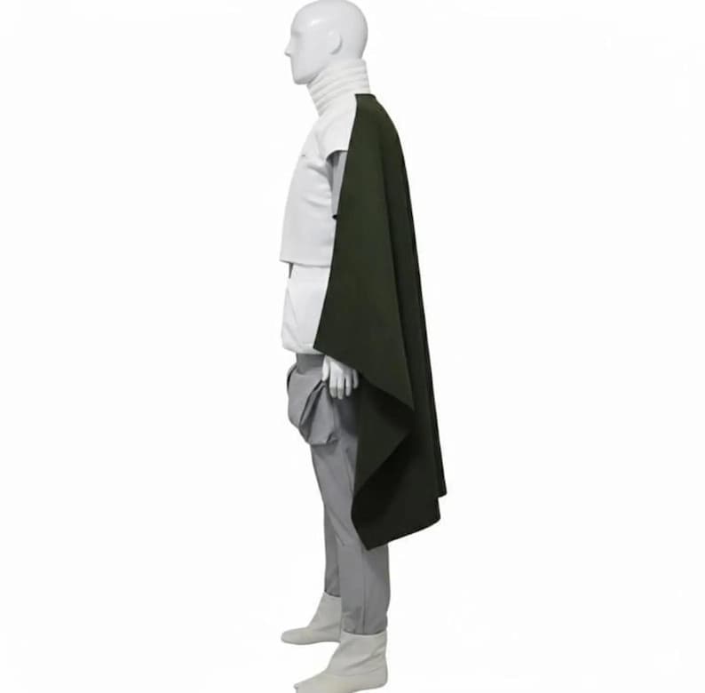 May include: A mannequin wearing a white turtleneck, white top, gray pants, and white boots. A dark green cape is draped over the mannequin's shoulder. The outfit is displayed against a white background.