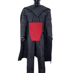Puede incluir: Un disfraz negro con cintur&oacute;n rojo y capa. El atuendo presenta patrones geom&eacute;tricos y costuras blancas. El disfraz se exhibe en un maniqu&iacute;, mostrando el dise&ntilde;o de cuerpo completo.