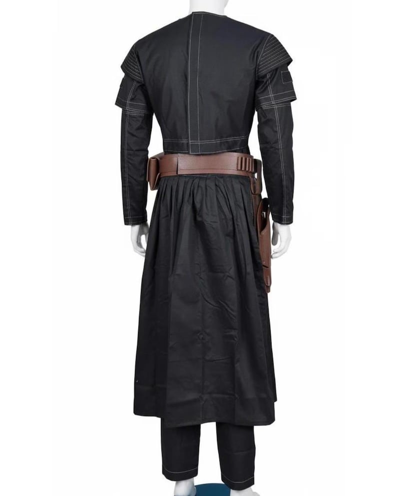 May include: Black costume with a long skirt, long-sleeved jacket, and brown belt. The jacket has white stitching and shoulder accents. A brown holster is attached to the belt. The costume is displayed on a mannequin.