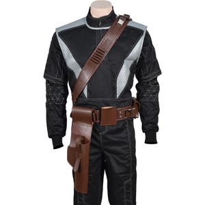 May include: Black jumpsuit with silver accents and brown leather accessories. The costume includes a shoulder strap, belt, and holster. The jumpsuit has geometric patterns on the sleeves.