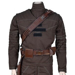 May include: Brown costume with a high collar, long sleeves, and white stitching details. It features a brown leather shoulder strap, belt, and pouches. The costume has a military or sci-fi theme.