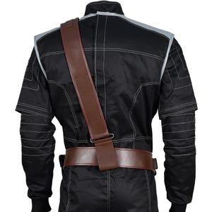 May include: Black jumpsuit with white stitching and gray accents. A brown leather belt and shoulder strap are visible. The jumpsuit has long sleeves and a high collar. The stitching creates a grid-like pattern across the garment.