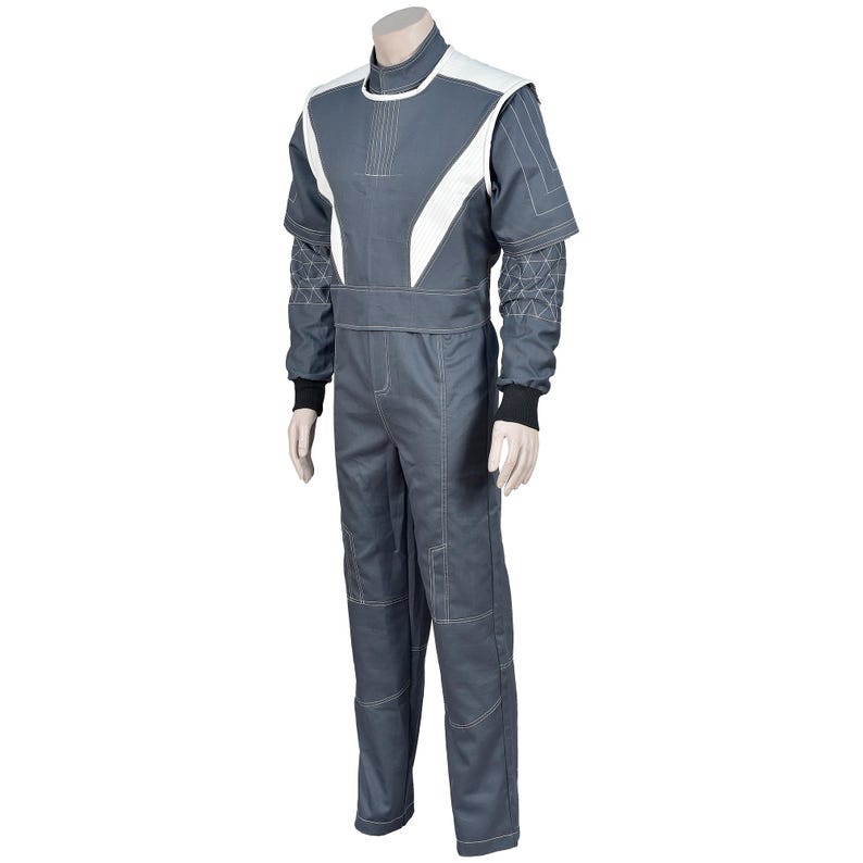 May include: A gray racing suit with white accents on the shoulders and chest. The suit has long sleeves with black cuffs and geometric patterned detailing on the upper arms. White stitching outlines the seams.
