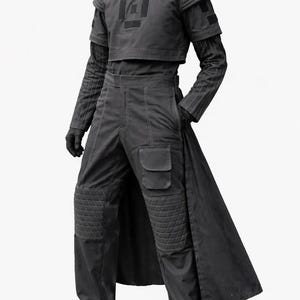 K&ouml;nnte beinhalten: Ein dunkelgraues futuristisches Outfit. Das Ensemble umfasst ein kurzes Oberteil mit quadratischem Design, ein lang&auml;rmeliges gestreiftes Unterhemd, eine hoch taillierte Hose mit Tasche und einen langen Mantel. Die Hose hat gesteppte Kniesch&uuml;tzer. Das Outfit wird durch Handschuhe und Schuhe vervollst&auml;ndigt.