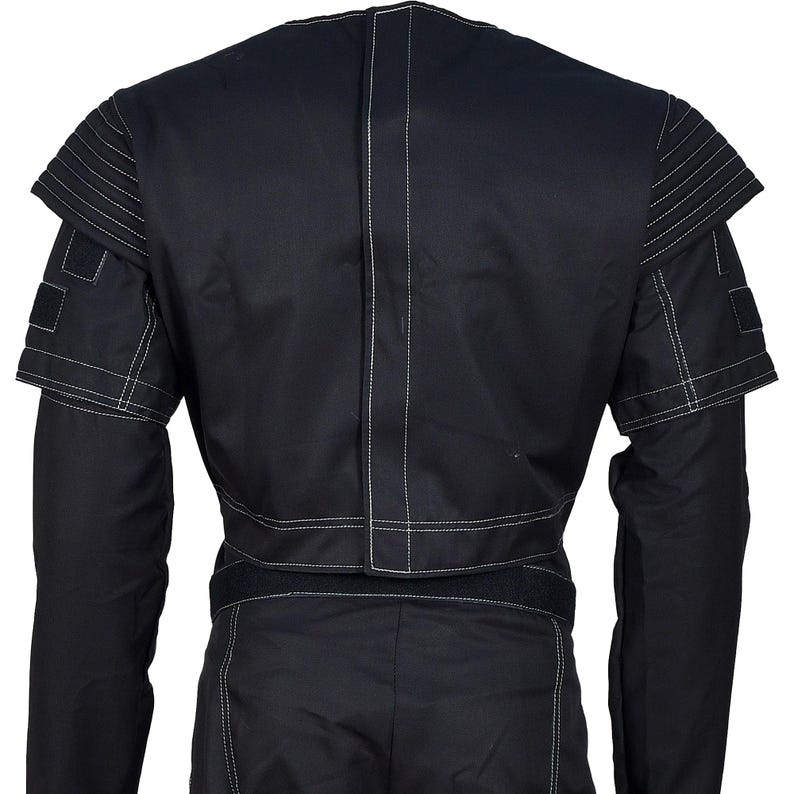 May include: Black jacket with white stitching details. The jacket features a unique design with layered shoulder accents and a fitted waist. The sleeves are long, and the back of the jacket is visible, showcasing the stitching.