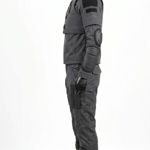 Pu&ograve; includere: Un set di uniforme tattica grigio scuro composto da una giacca a maniche lunghe e pantaloni abbinati. La giacca presenta un colletto alto, toppe in velcro nere e gomitiere integrate. I pantaloni includono tasche cargo e ginocchiere.