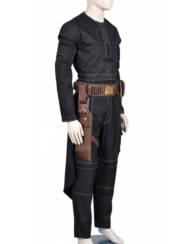 May include: Black costume with white stitching details. The outfit includes a long-sleeved top, pants, and a brown leather belt with a holster. The top has a round neck and padded shoulders. The costume is displayed on a mannequin.
