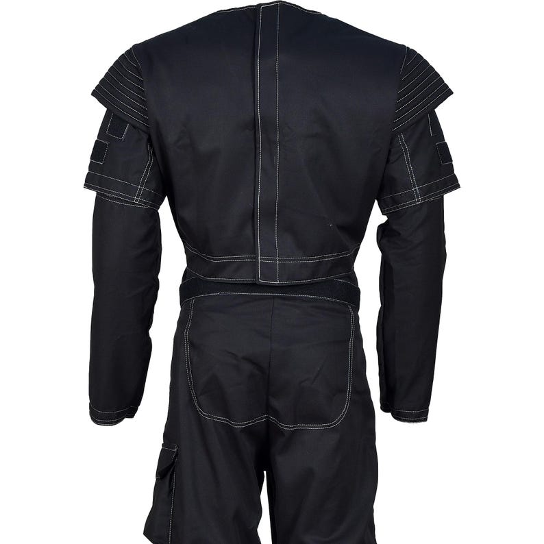 May include: Black jumpsuit with white stitching details. The garment features long sleeves, a structured shoulder design, and cargo pockets on the shorts. The back view showcases the tailored fit and contrasting white stitching.