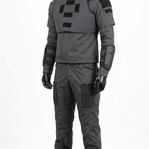Pu&ograve; includere: Un set di uniforme tattica grigio scuro composto da una maglia a maniche lunghe con collo alto, una piastra pettorale con toppe rettangolari nere, pantaloni abbinati, gomitiere e ginocchiere nere e stivali neri indossati da un manichino nero.