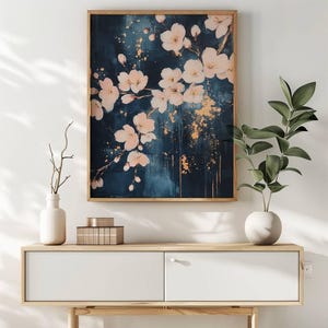 May include: A rectangular wall art piece in a wooden frame featuring a dark navy blue background with pale pink cherry blossoms and gold paint splatters. The artwork depicts delicate floral branches extending across the canvas surface.