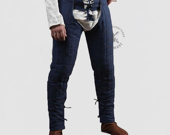 May include: Navy blue padded pants with a white front panel and lace-up closure. The pants have a quilted design and are likely part of a historical costume or reenactment outfit. The pants are shown with brown shoes.