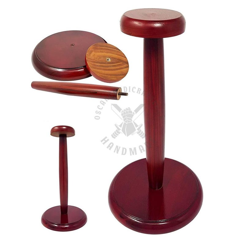 May include: Wooden helmet stands in a deep red stain. The stands have a circular base, a central post, and a circular top. One stand is assembled, while others are disassembled, showing the individual components. The stands are made of wood.