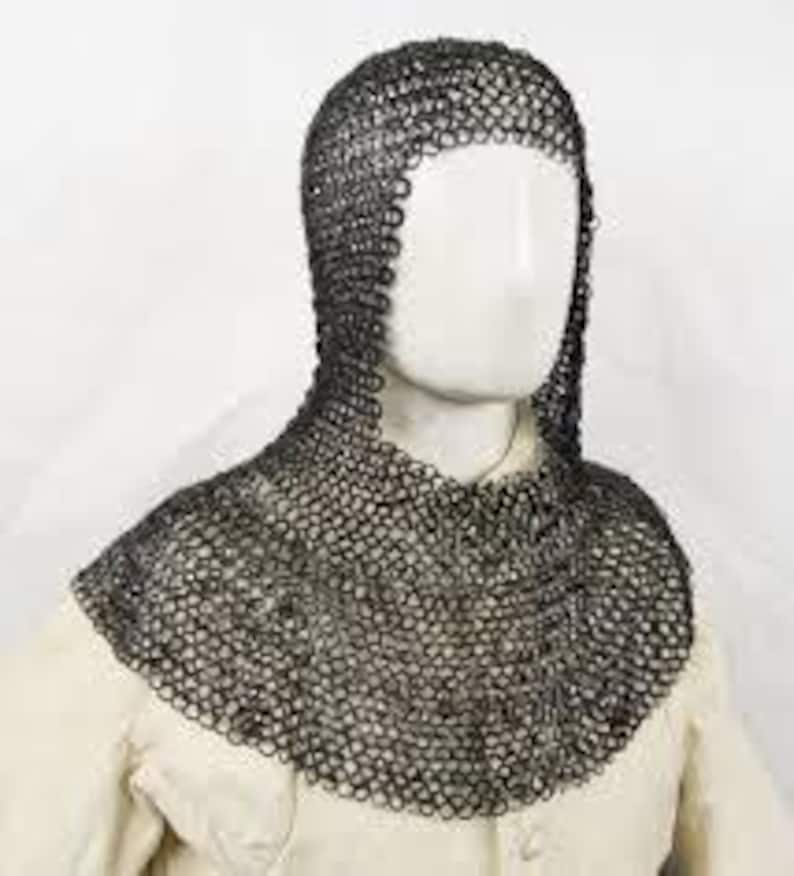 May include: A chainmail coif, a type of medieval head and neck protection, is displayed on a mannequin. The coif is constructed of small, interlocking metal rings, providing flexible yet robust defense. The coif is dark gray and covers the head, neck, and shoulders.