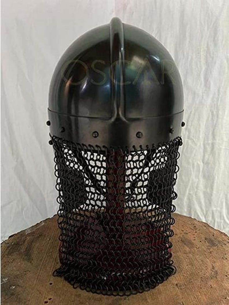 May include: A black metal helmet with a rounded top and a chainmail face guard. The helmet has a dark, reflective surface and is riveted at the base. The chainmail is made of small, interlocking rings.