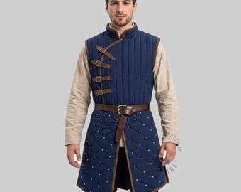May include: A navy blue quilted vest featuring a high collar, vertical stitching on the upper chest, and a diamond-patterned lower section with small silver studs. The garment includes a brown leather belt and four side-fastening leather straps.