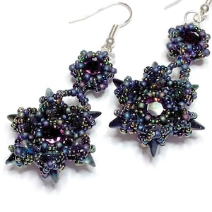 May include: A pair of dangle earrings with a starburst design. The earrings are made of silver and feature iridescent purple and green beads.