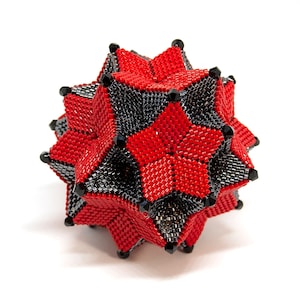 May include: A red and black beaded geometric sphere with a star-shaped design. The sphere is made of small beads and has a shiny finish.