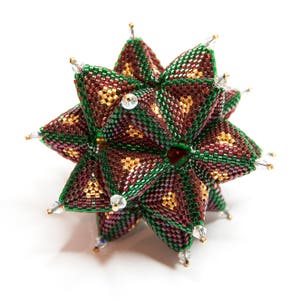 May include: A green, brown, and gold beaded star ornament with a geometric design. The star is made of small beads and has a three-dimensional shape.