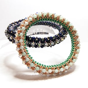 Op de afbeelding: Drie kralenarmbanden die op elkaar gestapeld zijn. De bovenste armband is groen, wit en koper. De middelste armband is donkerblauw en zilver. De onderste armband is donkerblauw en zilver.