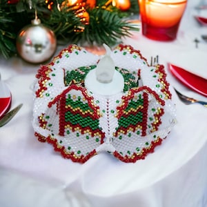 May include: A white, red, and green beaded candle holder with a white LED candle inside. The holder is shaped like a flower with a scalloped edge.