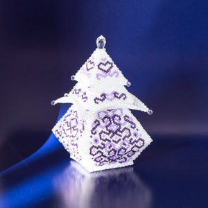 May include: A white and purple beaded Christmas tree ornament with a geometric design. The ornament is made of small beads and has a shiny finish.